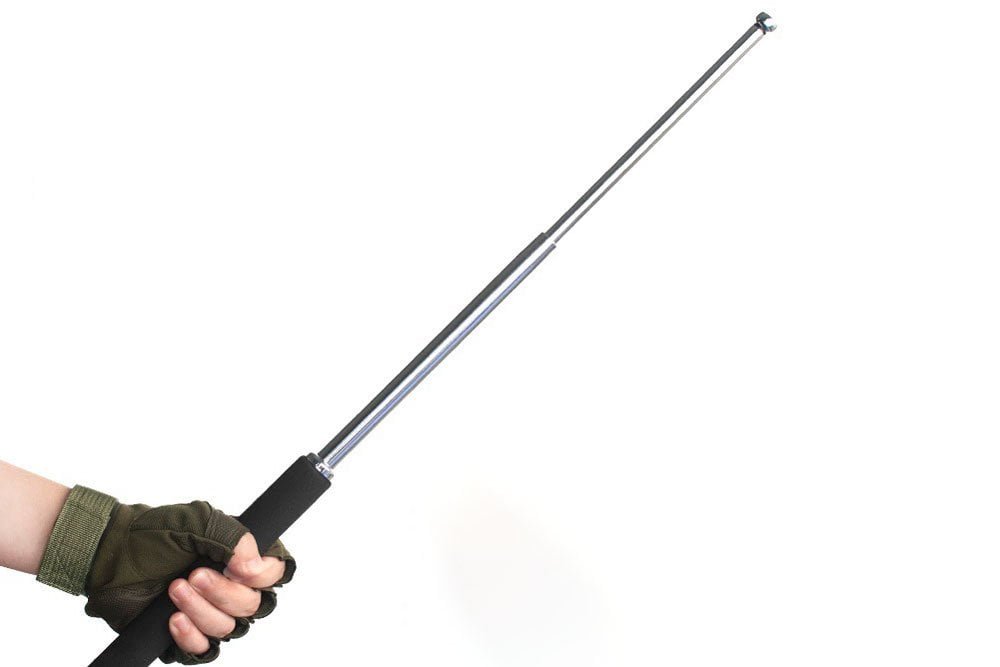 A close-up of a hand holding an expandable steel baton with a textured grip