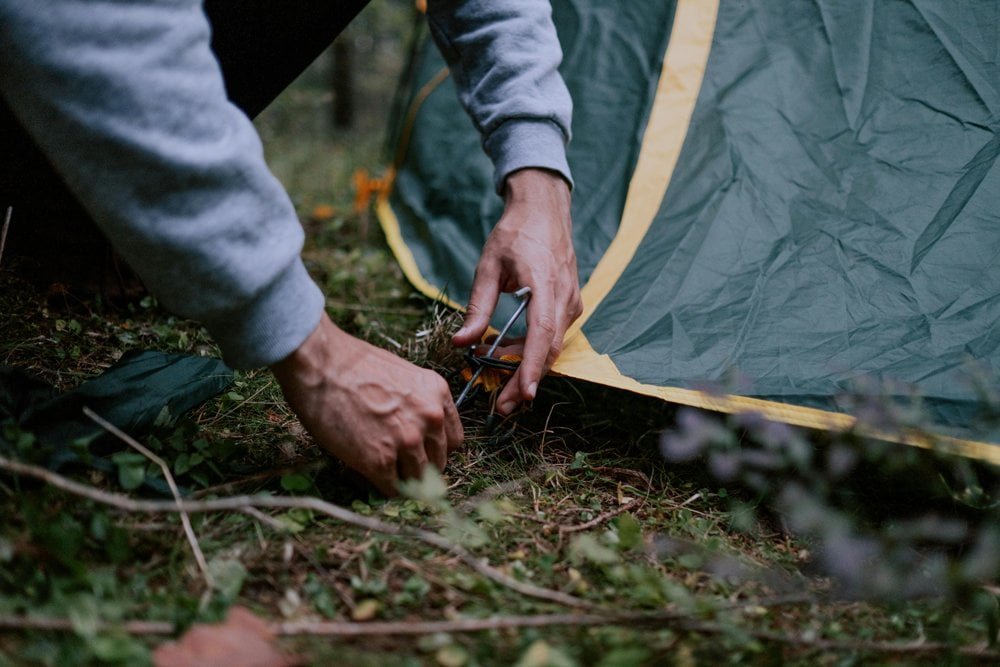 Man pitching a tent at night using a headlamp camper setting up tent with headlamp