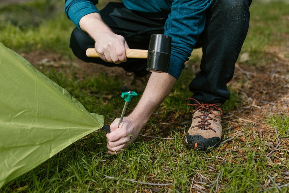 Person hammering tent pegs with both hands free hands-free tent setup