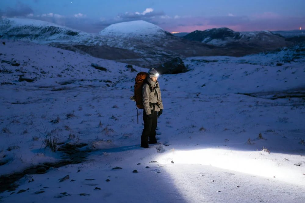 Hiker with headlamp at night Hiker using a headlamp on a trail
