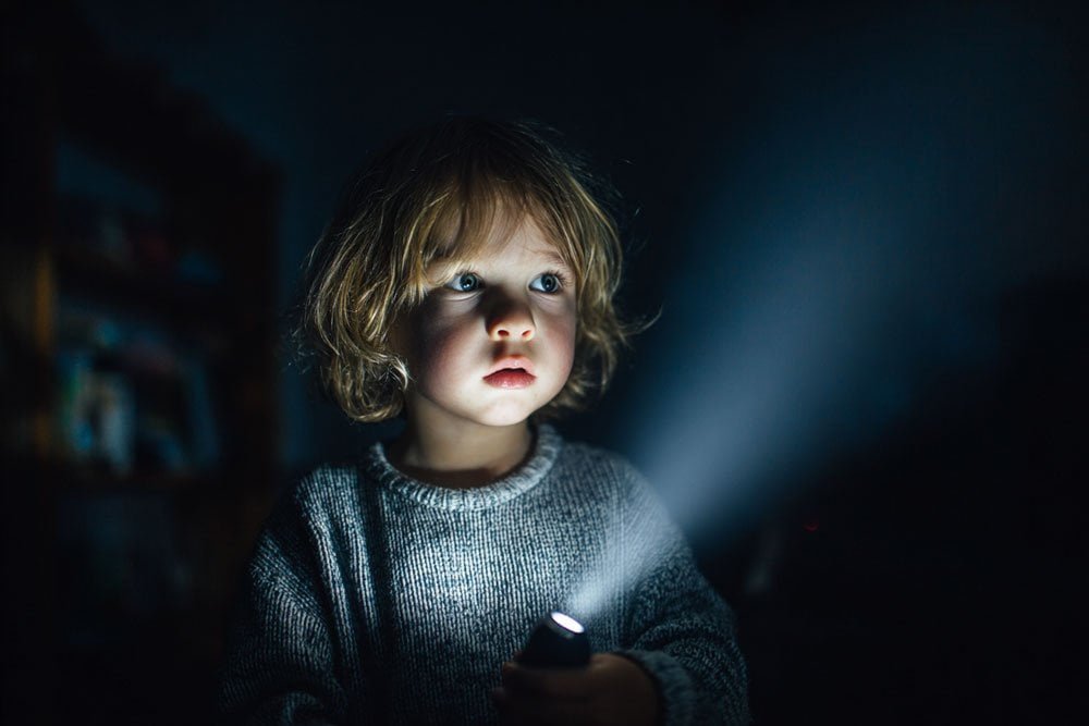 child exploring dark room with flashlight