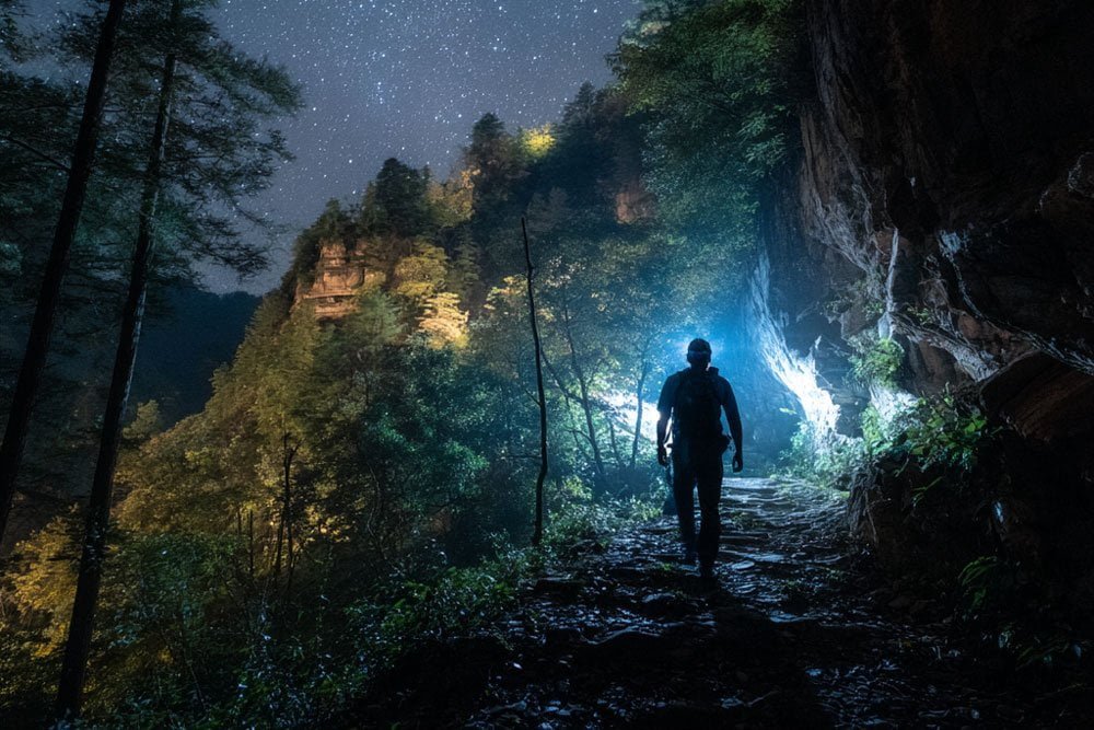 hiker preparing a rechargeable headlamp and spare battery before a trip